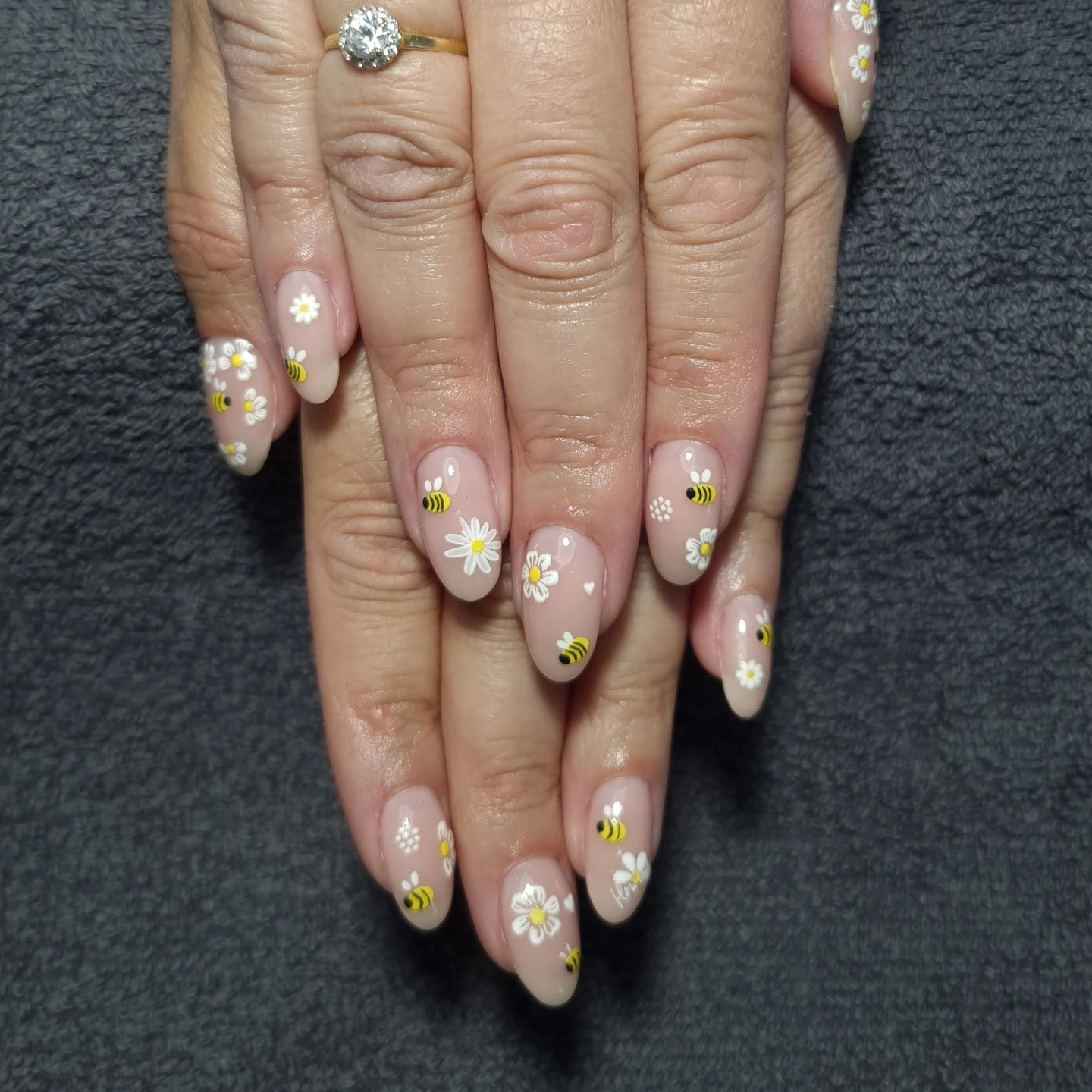 Manucure avec nail art floral et motifs d'abeilles sur ongles rosés.