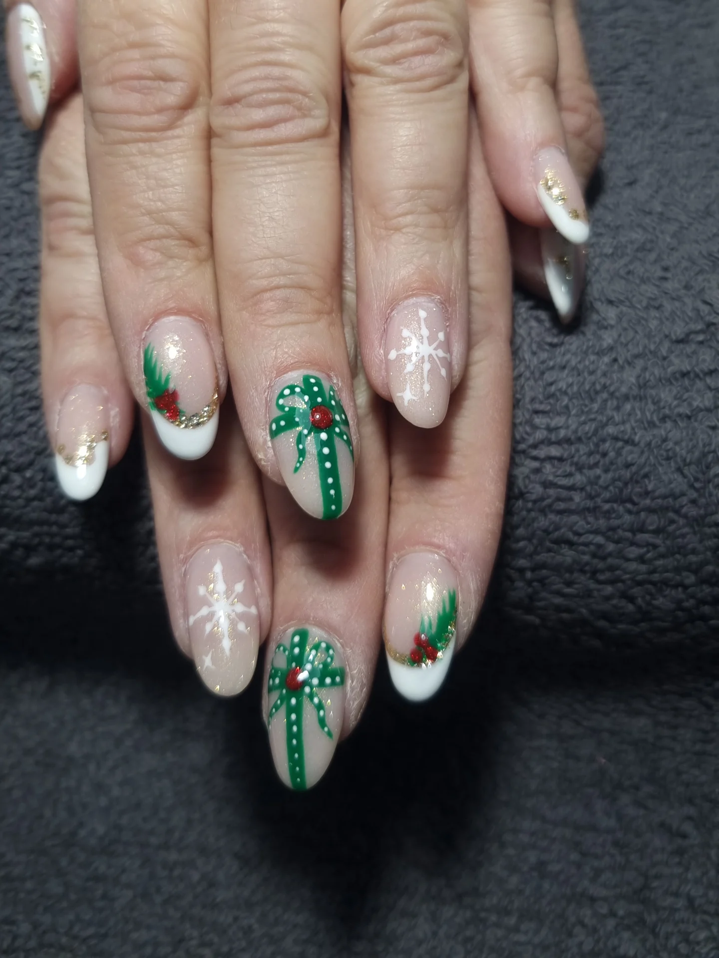Manucure artistique de Noël avec motifs de sapins, flocons et dorures sur ongles.